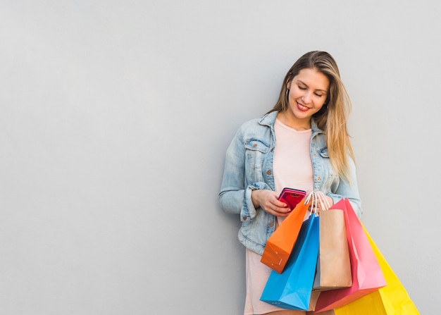 Pretty woman with shopping bags using smartphone