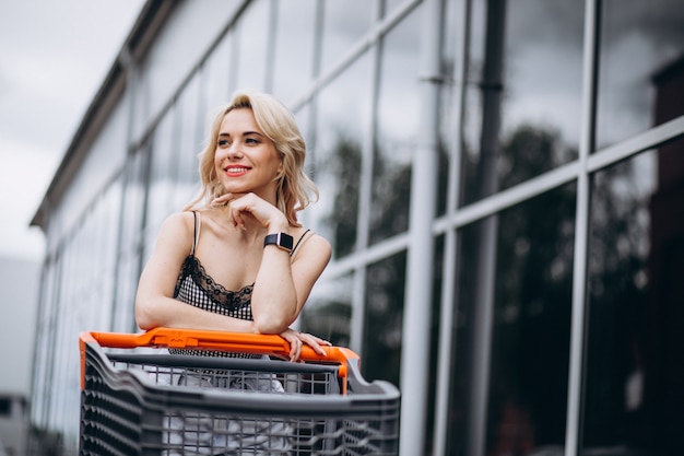 Free photo pretty woman with shopping cart outside