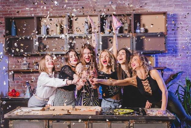 Free photo pretty women clinking glasses in confetti