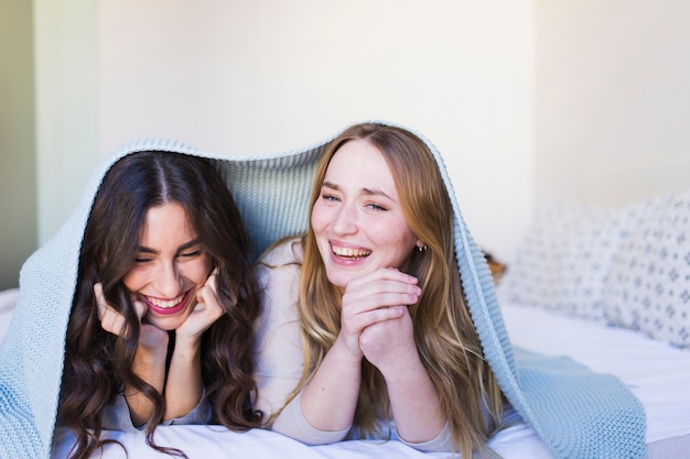 Free photo pretty women laughing under blanket