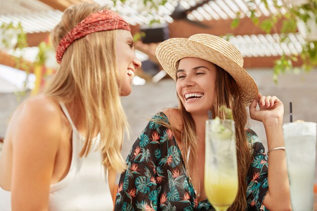 pretty women recreate together at coffee shop, drink fresh cocktails . Relaxed adorable females relax during summer holidays.