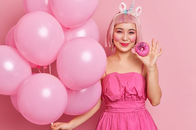 Pretty young Asian woman holds delicious doughnut