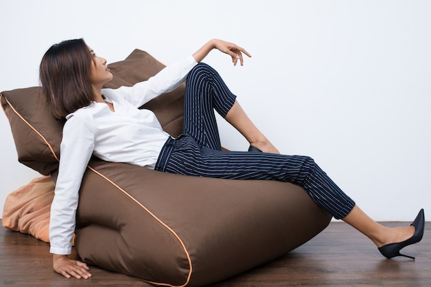 Free photo pretty young asian woman resting on beanbag chair