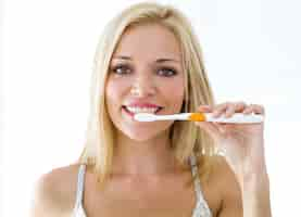 Free photo pretty young blonde woman cleaning her teeth.