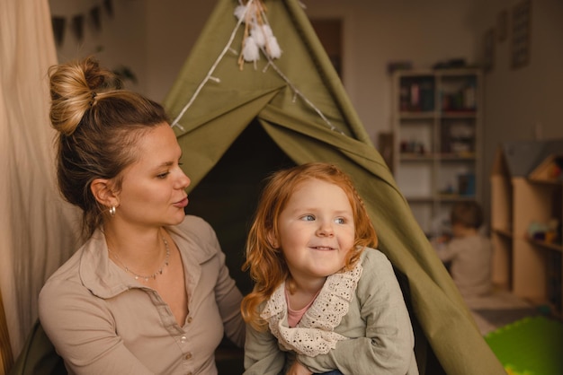 Free photo pretty young caucasian mother and little redhead daughter spend time together at home on weekends children concept