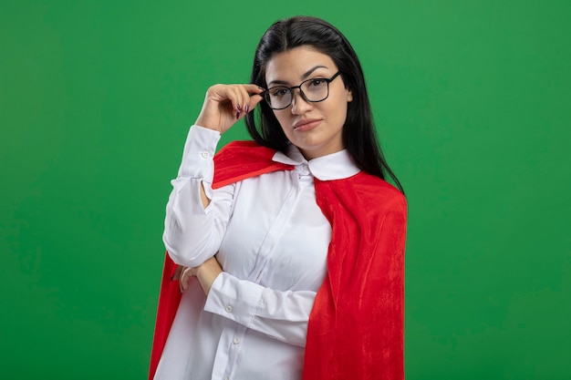 Pretty young caucasian superhero girl isolated on green wall