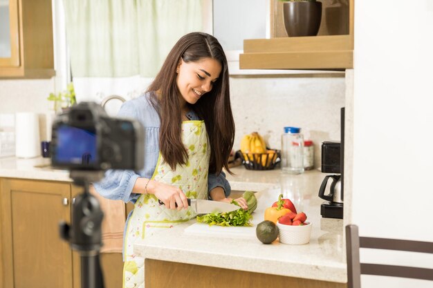 Pretty young female blogger recording a video and cooking a dish for her food vlog