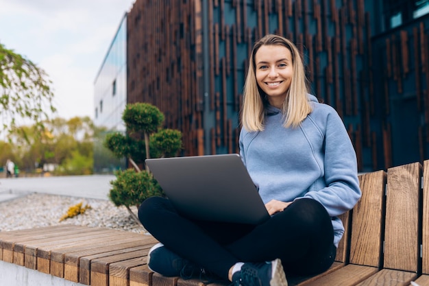 Pretty young female with laptop working studying at park