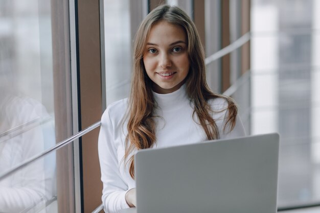 Pretty young girl with laptop by the window