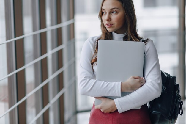 Pretty young girl with a laptop by the window