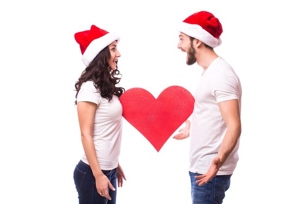 Free Photo pretty young santa couple friends man woman christmas hat hold big empty blank heart isolated on white background studio. happy new year celebration merry holiday concept