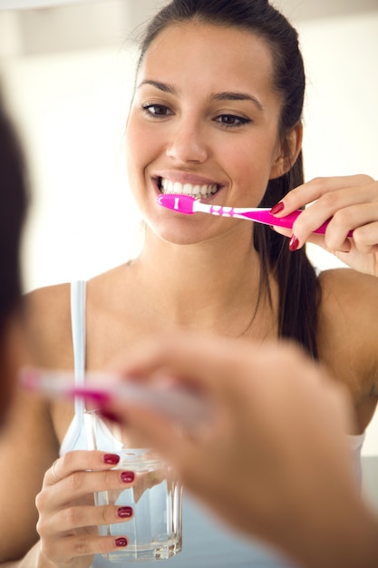 Free photo pretty young woman brushing her teeth in the bathroom.