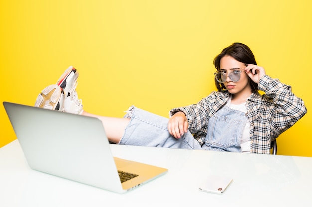 Free photo pretty young woman having a nap with foot in his desk with laptop isolated