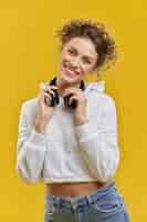 Free photo pretty young woman holding earphones on neck