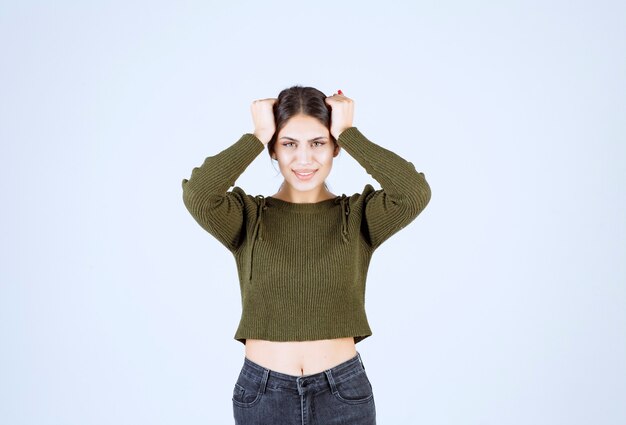 Pretty young woman holding her head with angry expression on white wall