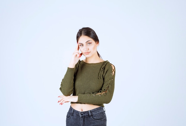 Pretty young woman posing with serious expression on white wall