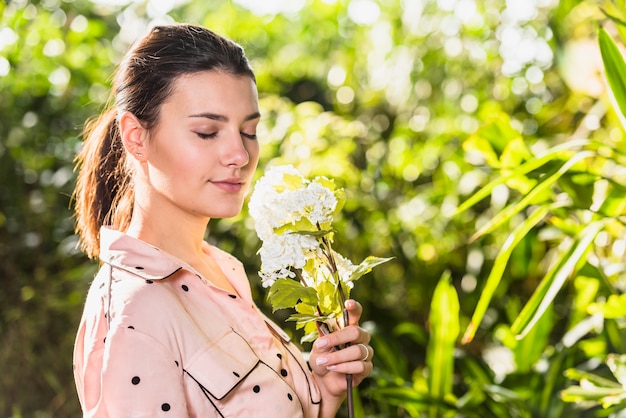 Pretty young woman smelling white flowers