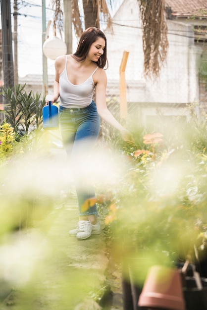 Free Photo pretty young woman taking care of plants in greenhouse