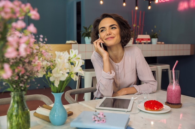 Pretty young woman talking on mobile phone while sitting