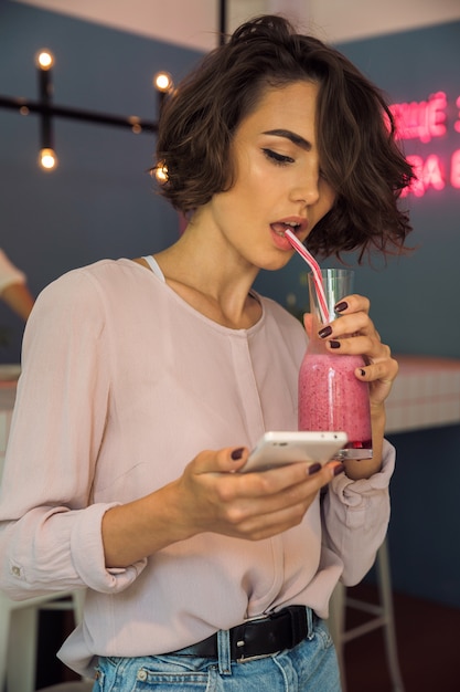 Free photo pretty young woman typing message on mobile phone