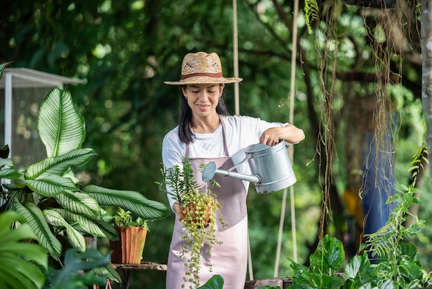 Pretty young woman watering tree in the garden at summer sunny day. woman gardening outside in summer nature. farming, gardening, agriculture and people concept.