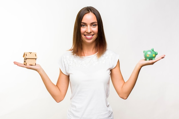 Free photo pretty young woman with a cottage and a piggy bank