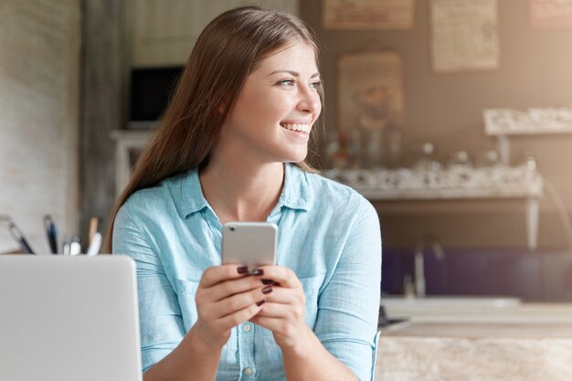 Pretty young woman with long hair sitting in cafe with laptop