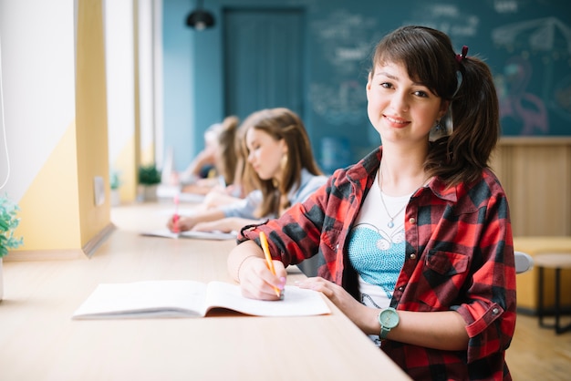 Free photo pretty youngster sitting at desk in class