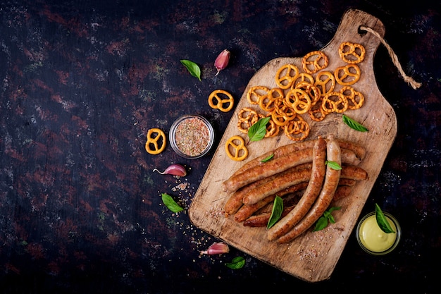 Free photo pretzels and grilled sausages on dark background. oktoberfest. flat lay. top view