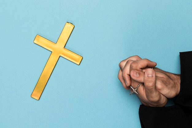 Priest praying with wood cross 