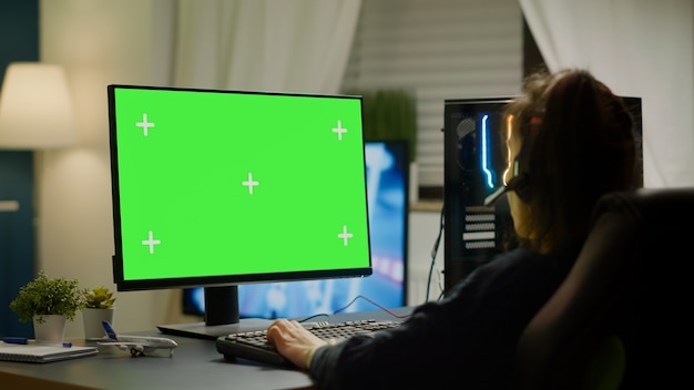 Free photo pro gamer playing virtual video game on powerful computer with green screen mock up, chroma key display. cyber player using professional pc with isolated desktop streaming shooter games wearing headse