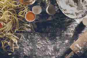 Free photo process of cooking pasta with raw fresh ingredients for classic italian food - raw eggs, flour on wooden table. top view. toning.