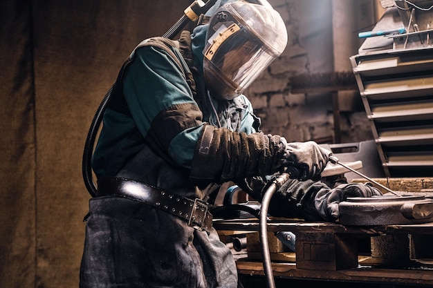 Process of creating new metal parts at busy workshop made by worker.