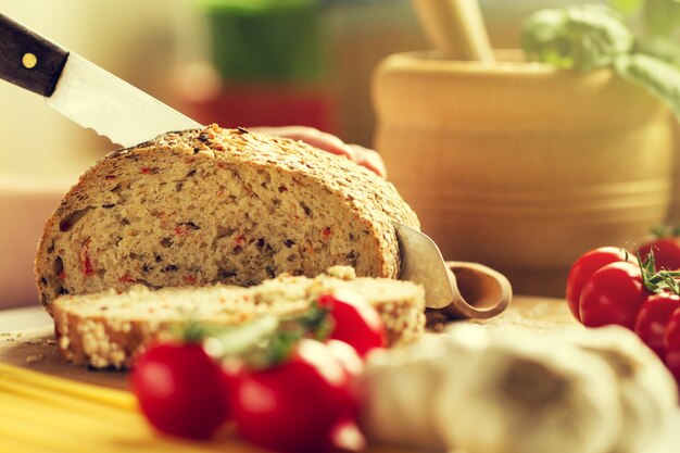 Process of cutting wholewheat bread in the kitchen. Kitchen Background. Cooking process. Toned.