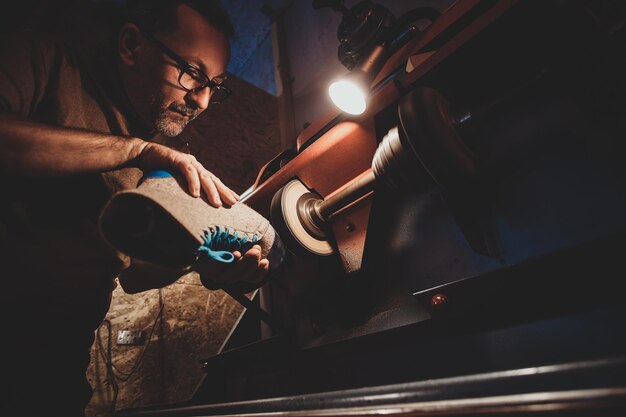 Process of making boots - master is making sole using special tool at workshop.