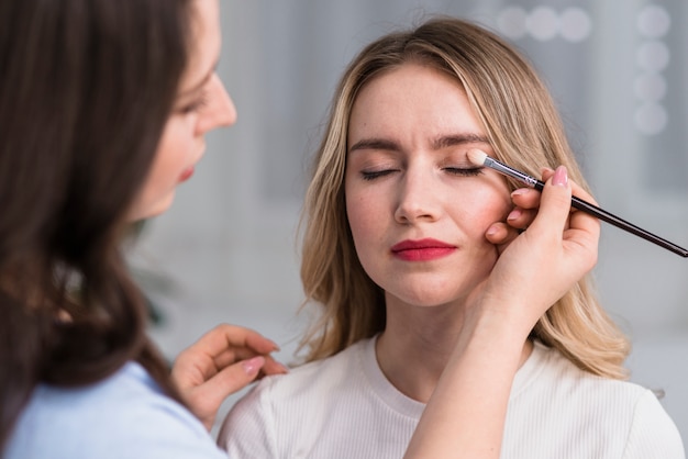 Process of making makeup to blond beautiful woman