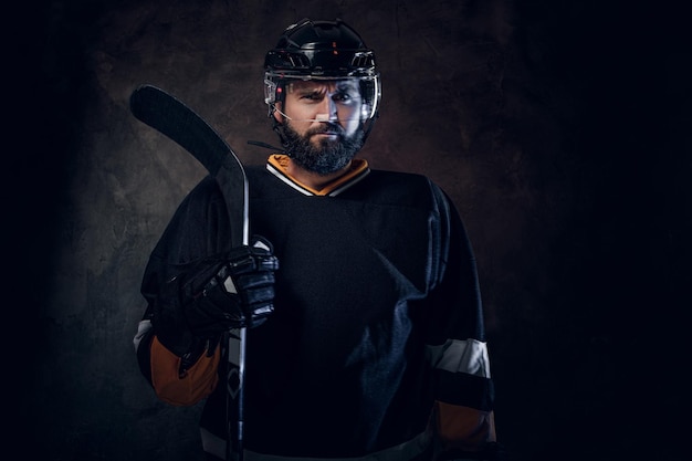 Professional bearded man in hockey player gear is posing for photographer.