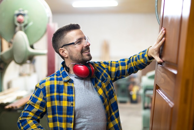 Free Photo professional blonde middle aged carpenter checking quality of wood product in his carpentry workshop