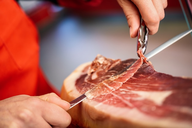 Free Photo professional cutter carving slices from a whole bone-in serrano ham