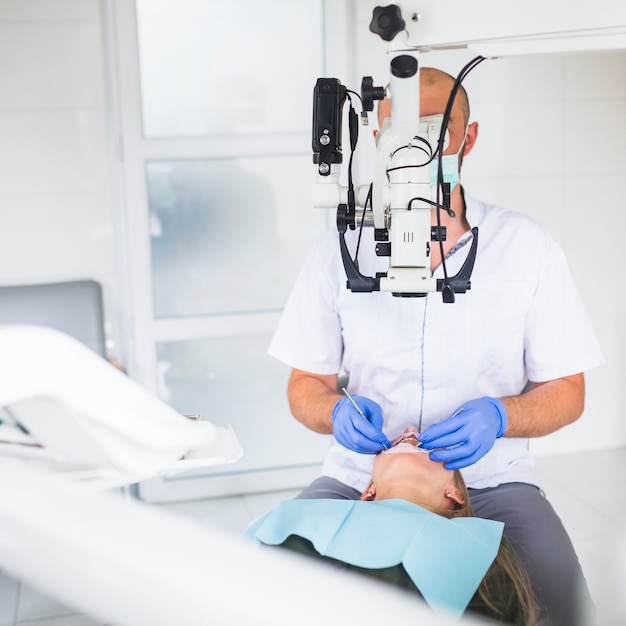 Free photo professional dentist examining patient with dental microscope