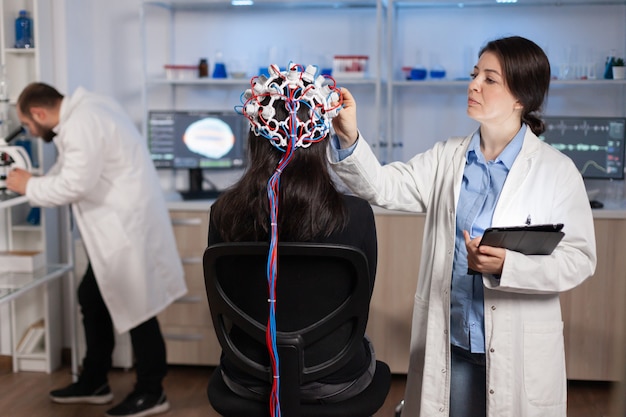 Free Photo professional doctor in neuroscience developing treatment for neurological diseases examining patient evolutions. doctor researcher adjusting eeg headset analyzing brain functions and health status.