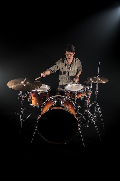 Professional drummer playing on drum set on stage on the black background with drum sticks and vintage look. Top view. Smoke effect