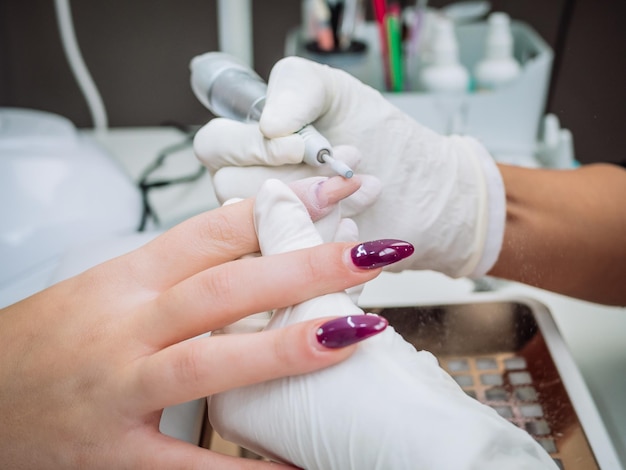 Free photo professional esthetician using an electric nail file drill to remove acrylic gel from nails