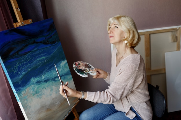 Free photo professional female artist painting on canvas