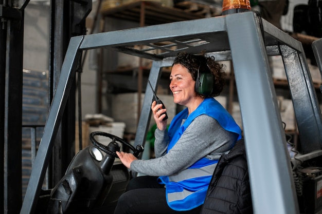 Free photo professional female driver operating forklift vehicle