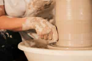 Free photo professional female potter smoothing clay on potter's wheel