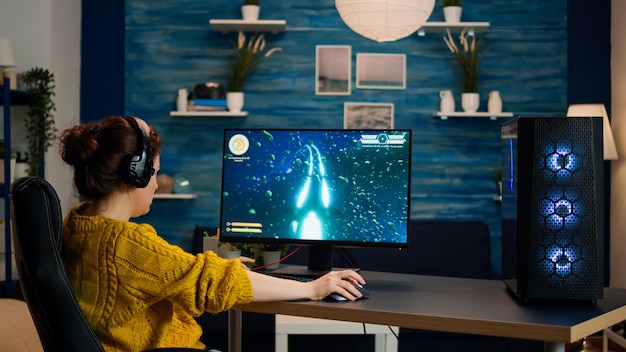 Professional gamer playing first-person shooter online video game on powerful personal computer with colorful neon led lights. Cyber performing on pc in stylish room during gaming tournament