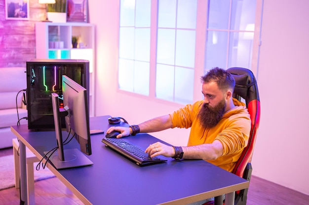 Free photo professional gamer with long beard in front of powerful gaming rig in room full of neon lights