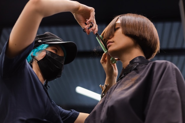 Free photo a professional girl hairdresser makes a client haircut. the girl is sitting in a mask in beauty the salon