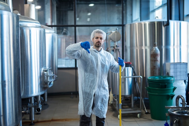 Free photo professional industrial cleaner in protective uniform holding thumbs down